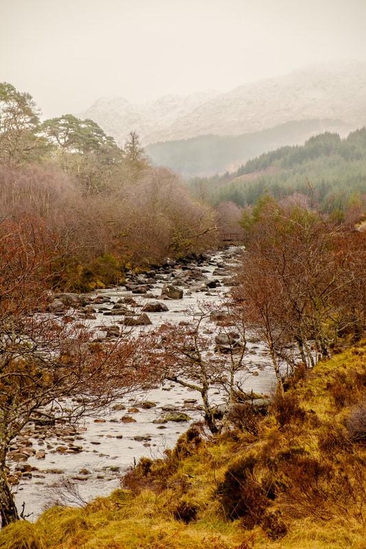 The River Strontian flowing through Ariundle Oakwood with the snow-covered peak of a misty Sgurr Dhomhnuill in the background | Sunart Scotland