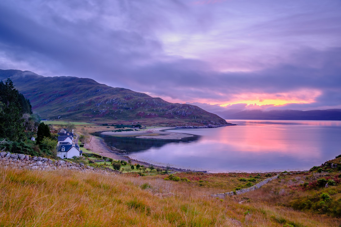Golden light of sunrise breaking through clouds beyond the bay at Camasnacroise causing pink to emerge from the colours of the blue hour | Ardgour Scotland