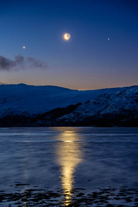 A waning crescent moon is reflected in Loch Sunart as it sits between Venus and Jupiter | Ardnamurchan Scotland | Steven Marshall Photography
