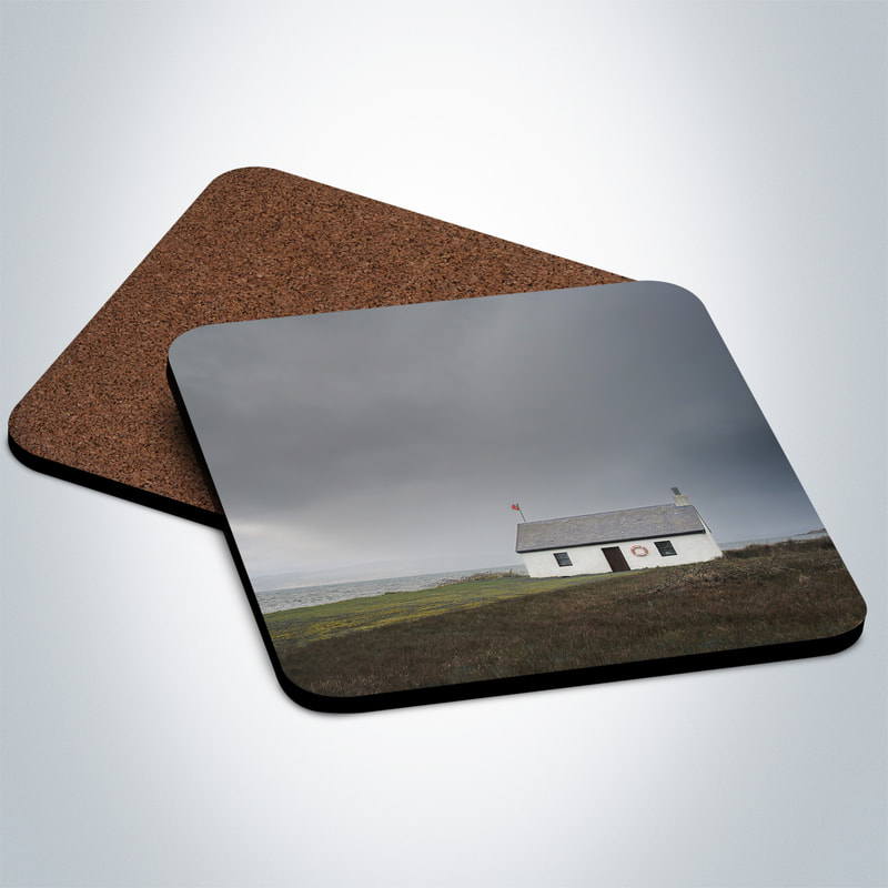 Souvenir photo coaster featuring an image of grey and imposing clouds filling the sky above the white Shore Cottage in Kilchoan as a storm approaches | Ardnamurchan Scotland