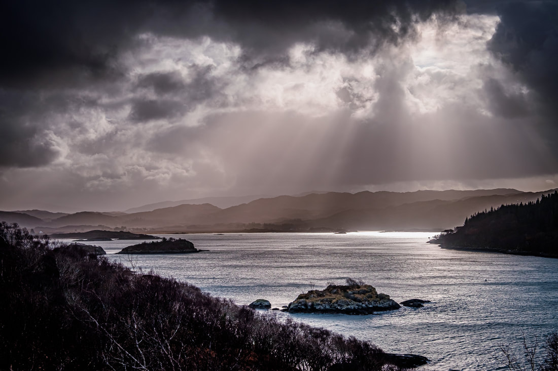 The view over Kentra Bay from Ardtoe in the aftermath of Storm Dennis with clearing clouds crepuscular rays to shine down onto the waters at its entrance | Ardnamurchan Scotland