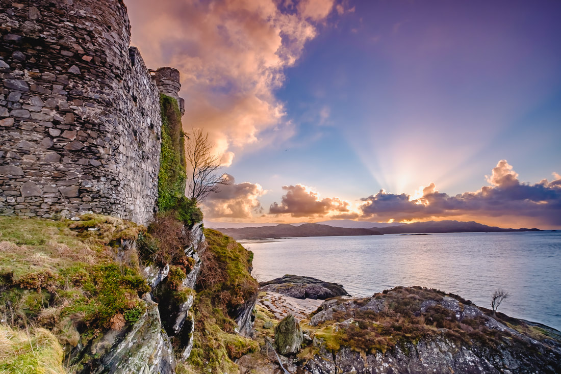 The north wall of Castle Tioram with the last rays of sunlight emerging from behind the clouds beyond it | Moidart Scotland