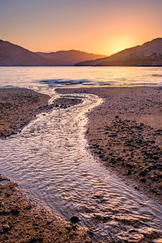Ardnastang Beach and Loch Sunart at sunset with the sun dipping below the hills to the west| Sunart Scotland