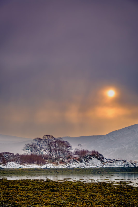 Morning sun breaking through the clouds of a snow shower as it makes its way up Loch Sunart | Sunart Scotland