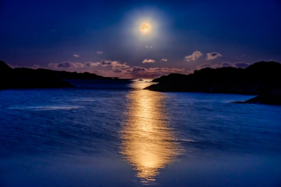 A golden full moon sitting above the horizon beyond the beach at Ardtoe with moonlight reflected on the sea | Ardnamurchan Scotland