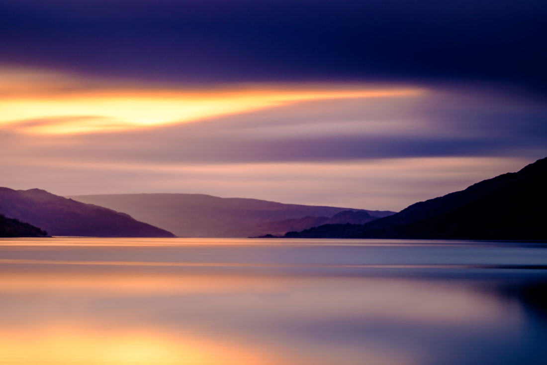 A long exposure capturing a gold and violet sunset over the calm waters of Loch Sunart | Sunart Scotland