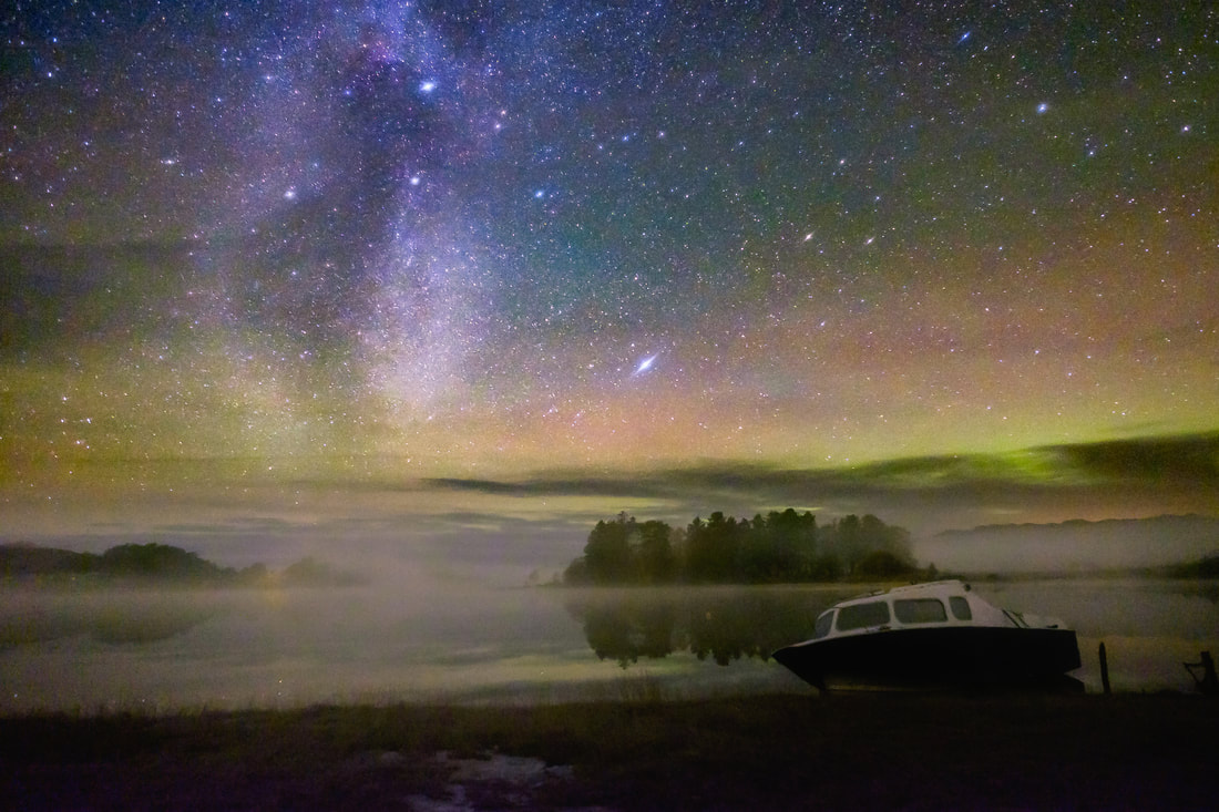 A small day boat lying at its winter resting place on the shore of Loch Shiel under a star-filled night sky and mist rolling across the Loch Shiel | Moidart Scotland