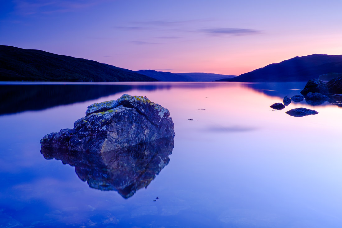 A large, submerged rock in a calm Loch Sunart at dusk with a background of blues and purples | Sunart Scotland