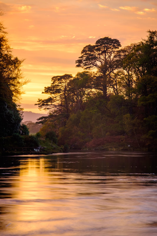 The sun setting beyond the end of the River Shiel with the river and sky in sunset colours | Moidart Scotland