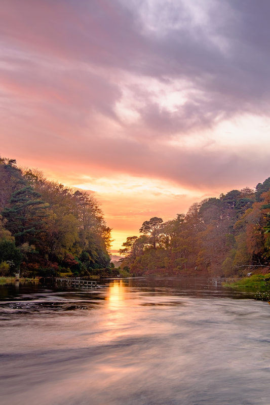 The sun setting beyond the end of the River Shiel with the river and sky in sunset colours | Moidart Scotland