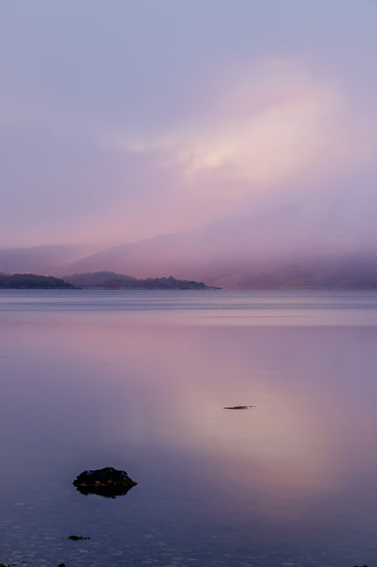A squally snow shower on Loch Sunart against a pink background from the light of the rising sun | Sunart Scotland