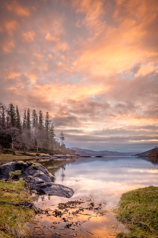 The calm waters of the Bay of Flies at sunset mirroring the clouds and sky| Ardnamurchan Scotland