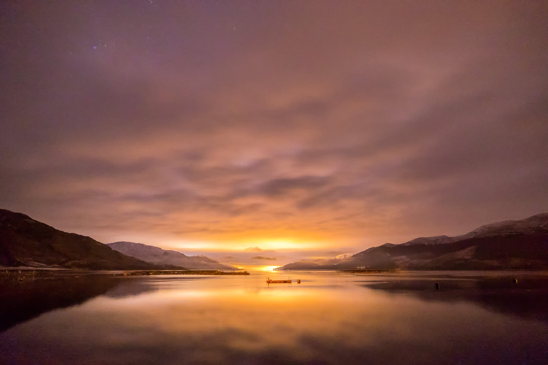 View up Loch Linnhe from Corran at night with the lights of Fort William illuminating the sky | Ardgour Scotland