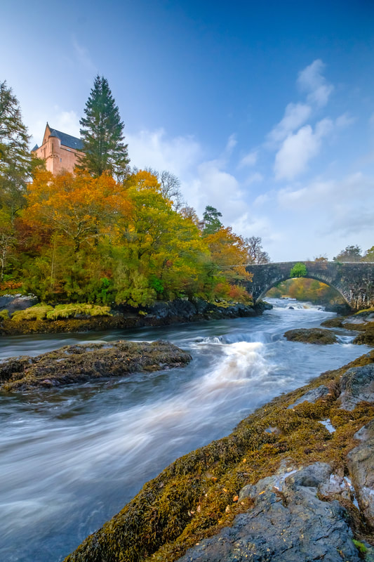 The River Aline with golden autumnal trees on its banks, flowing past Kinlochaline Castle and through seaweed covered rocks | Morvern Scotland
