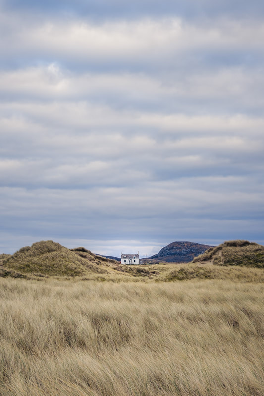A white croft house in between the sand dunes at Sanna with marram grass in the foreground | Ardnamurchan Scotland | Steven Marshall Photography