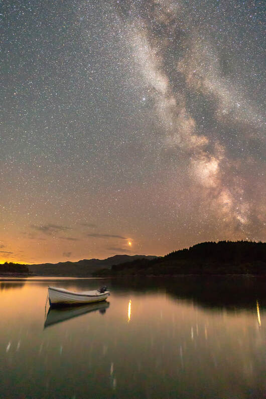 The Milky Way and Mars above a small boat moored in the calm water of Kentra Bay | Ardnamurchan, Scotland | Steven Marshall Photography