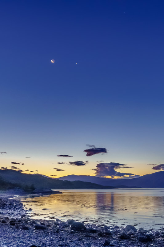 A waning crescent moon and Venus rising together above the orange glow of daybreak and Loch Sunart | Sunart Scotland
