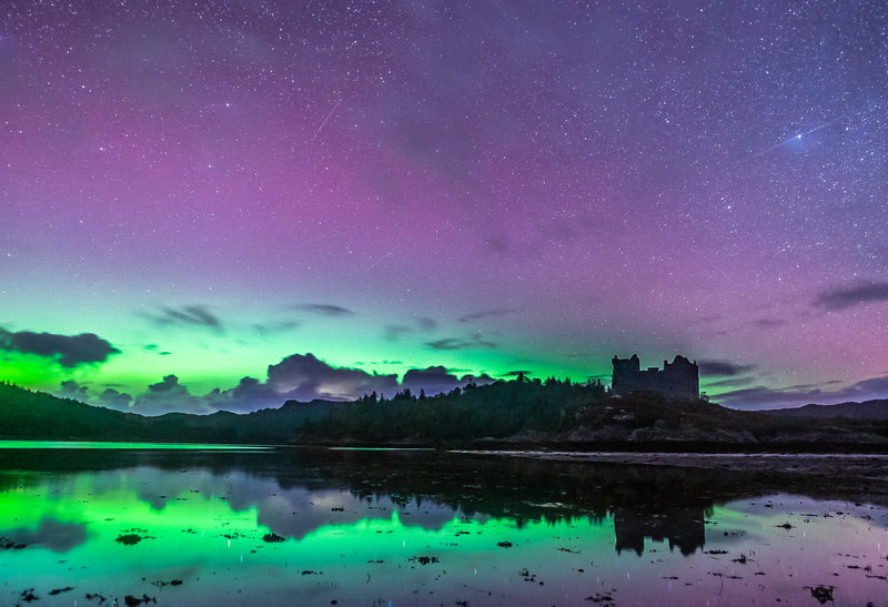 The sky above Castle Tioram and the sea below lit up with greens and purples from a spectacular show of the Northern Lights.