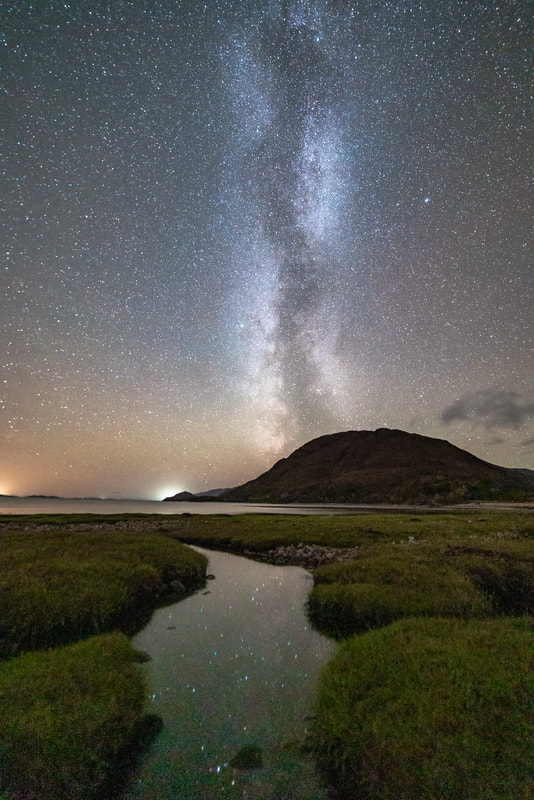 Reflections of stars in the pools of water in the salt marsh at Sallachan Beach with the Milky Way over the summit of Beinn Leamhain | Ardgour Scotland