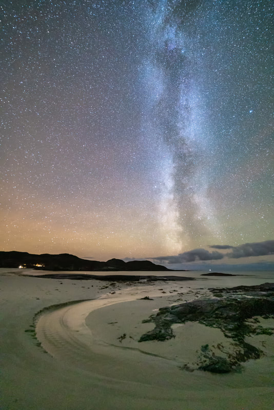 A stream flowing from the sand dunes at Sanna, winding round the rocks and then out to the sea with the Milky Way and a star-filled sky above it | Ardnamurchan Scotland