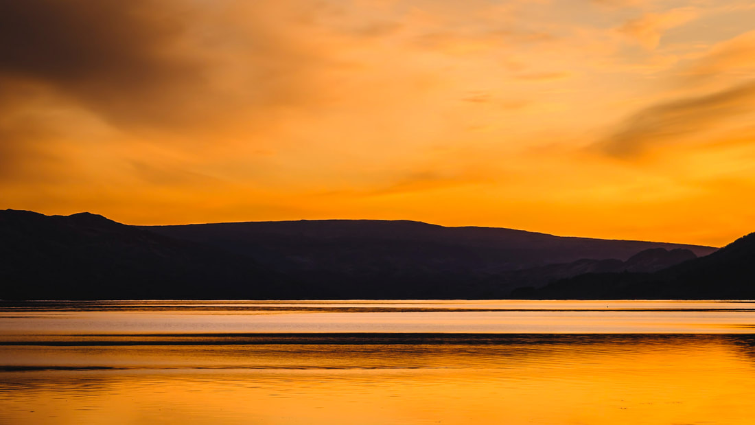 A vivid orange sunset with the hills of Morvern silhouetted against the sky and the sea loch | Sunart, Scotland | Steven Marshall Photography